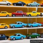 미니카 컬렉션 관리 방법 - A detailed close-up of a miniature car collection displayed inside a clear acrylic case with tiered ...